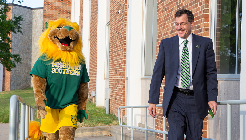 President Dean Van Galen walking with Lion mascot 