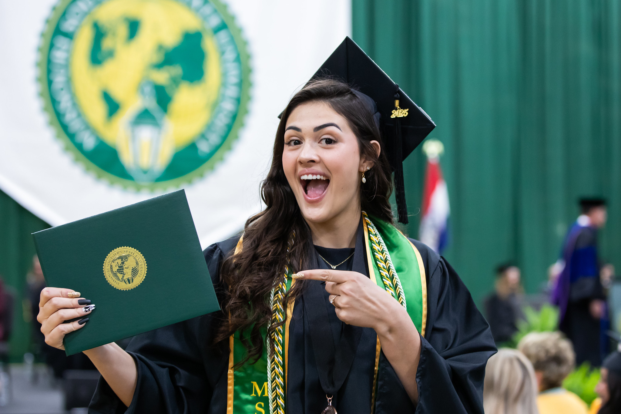 MSSU graduate holding diploma and smiling