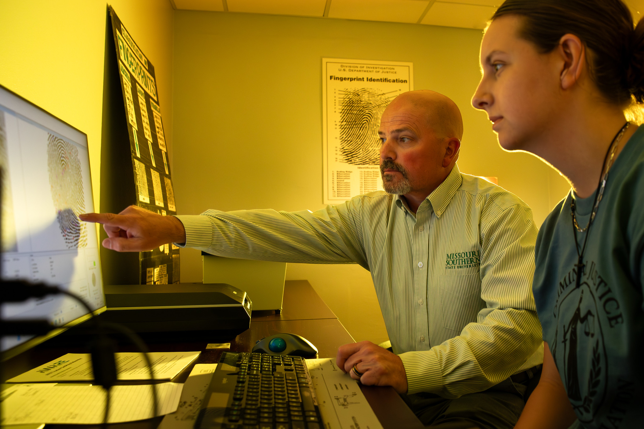 faculty member instructing student in front of computer 