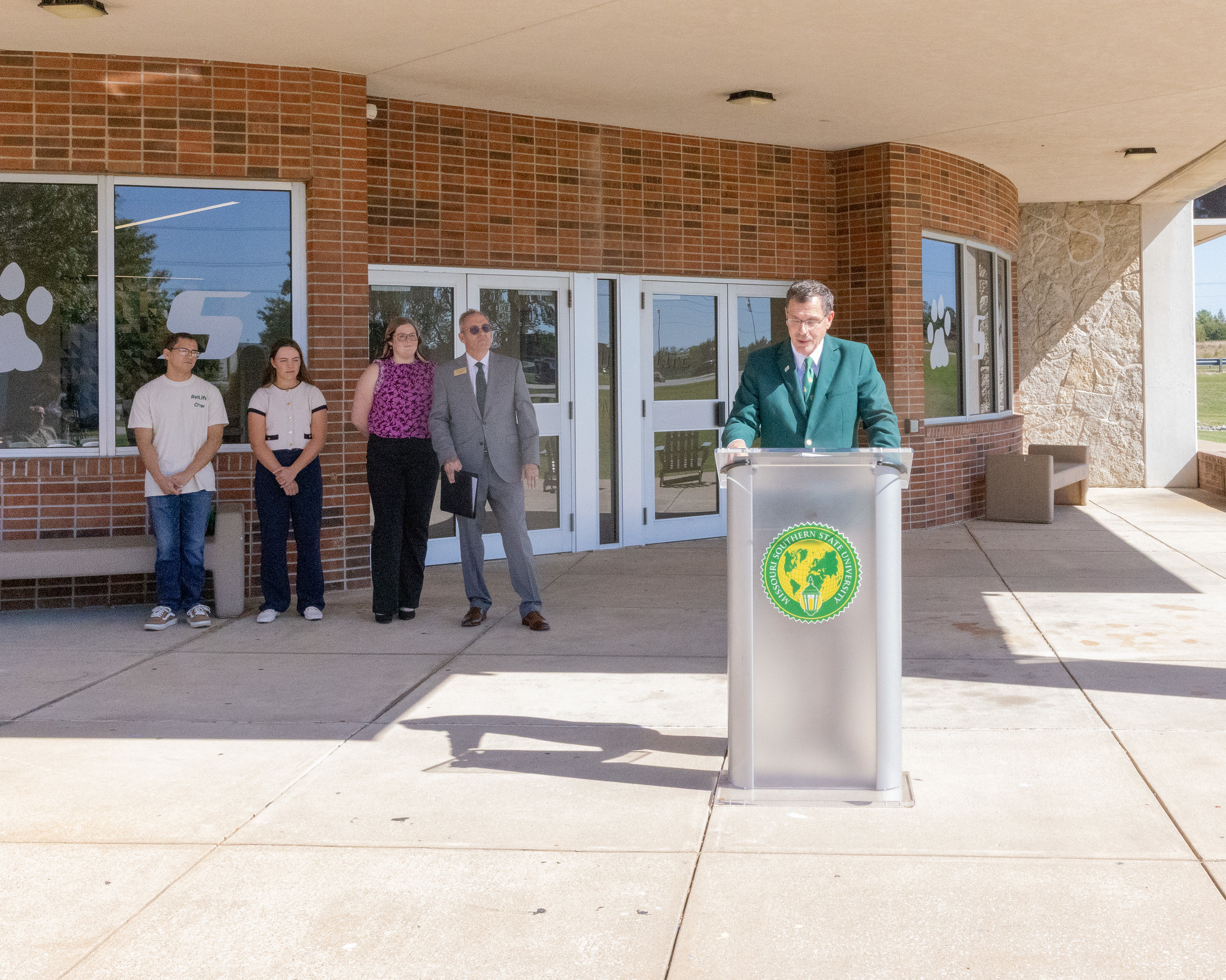 Dr. Van Galen addressing crowd with students standing beside him
