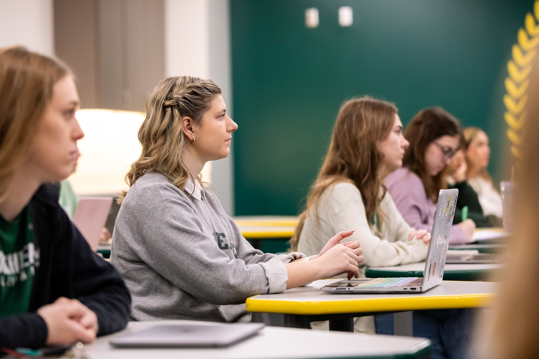 Student listening intently in classroom with laptop 