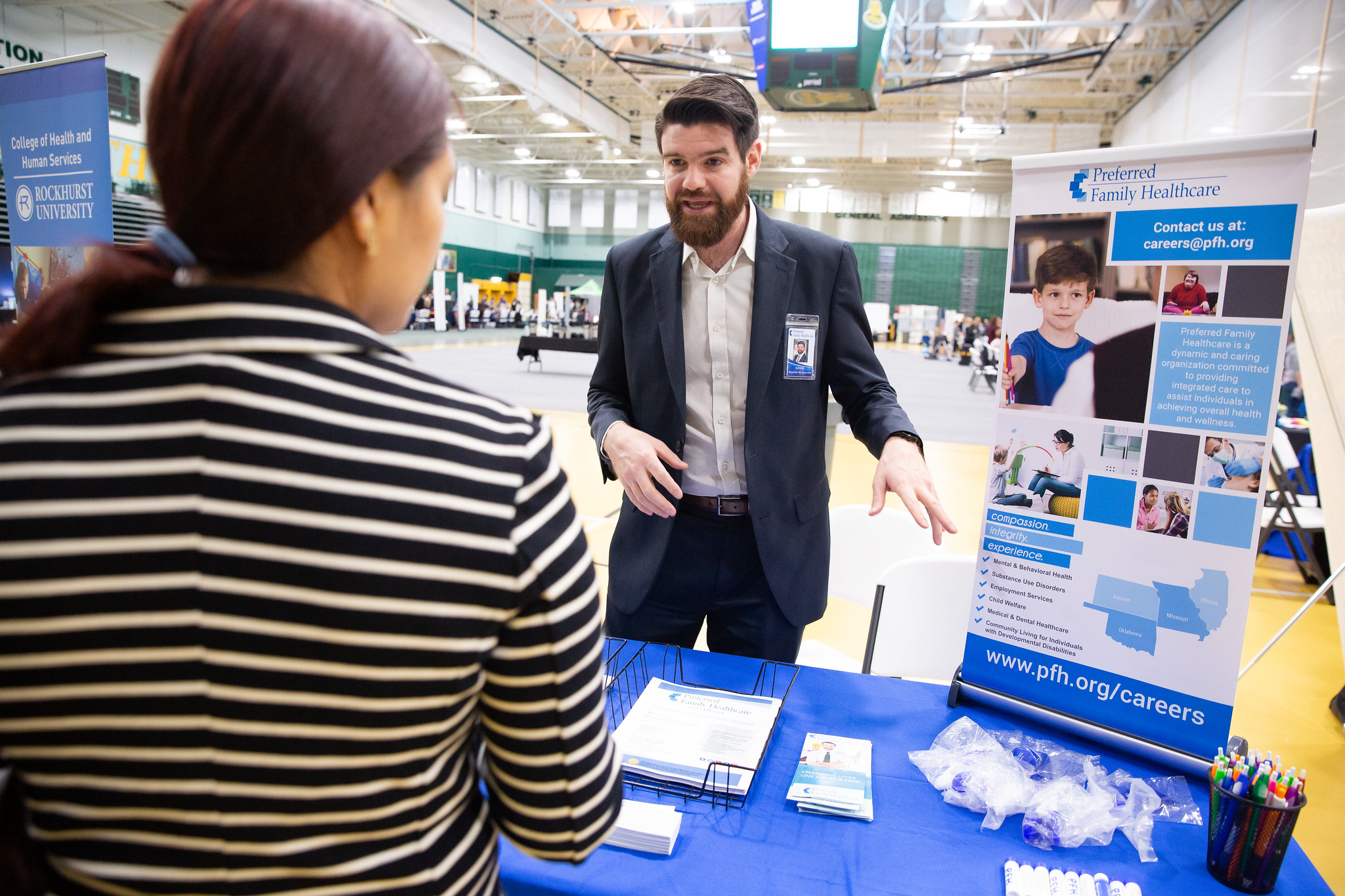 career fair employer standing at their booth talking to student 